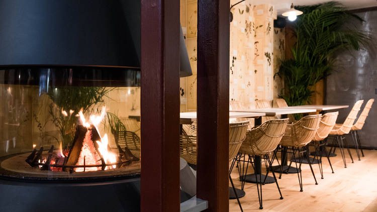 An Antipodea dining room with a central fireplace and rattan chairs