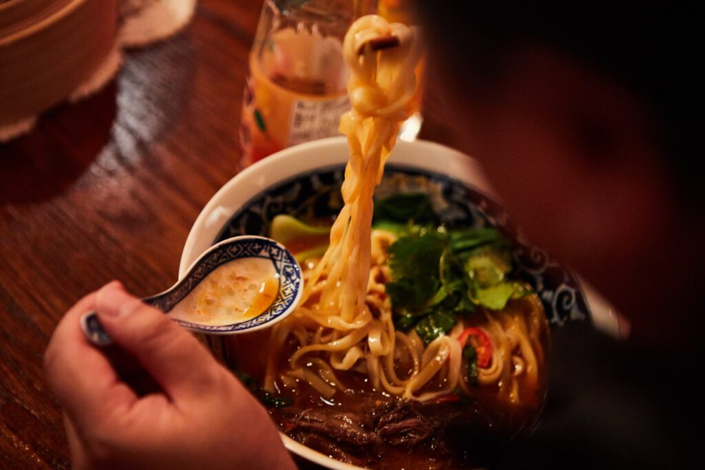 Taiwanese beef noodles lifted from the bowl with chopsticks