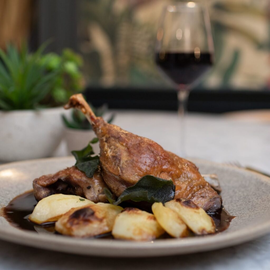Duck confit with roast potatoes and a glass of red wine