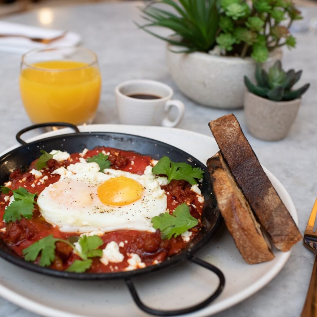 Shakshuka with a fried egg and feta, served with sourdough and orange juice