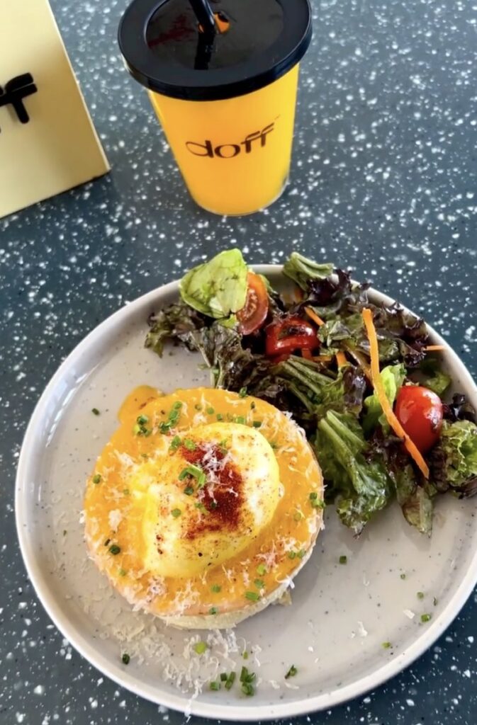 Eggs Benedict with salad and an iced coffee in a yellow Doff cup