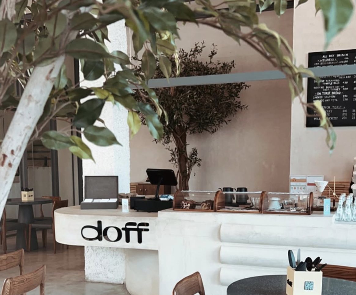 The Doff Coffee counter in Riyadh, with the logo set into a curved white bar beneath an olive tree