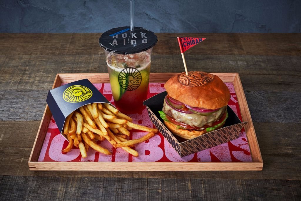 A wagyu burger with fries and a drink on a printed ICHIBUNS tray