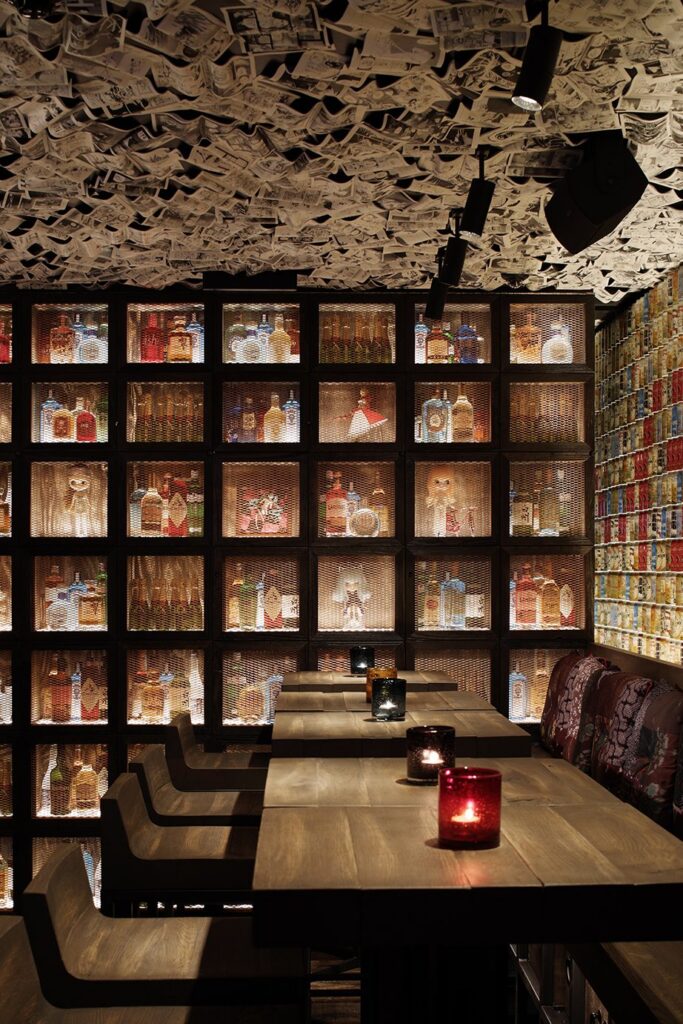 A wall of lit cabinets and red lamps beside dining tables at ICHIBUNS