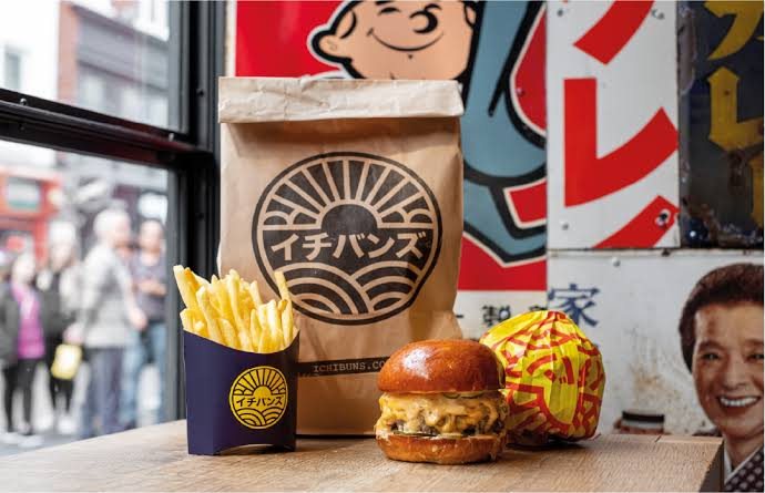 A burger, fries and branded takeaway bag in the ICHIBUNS window