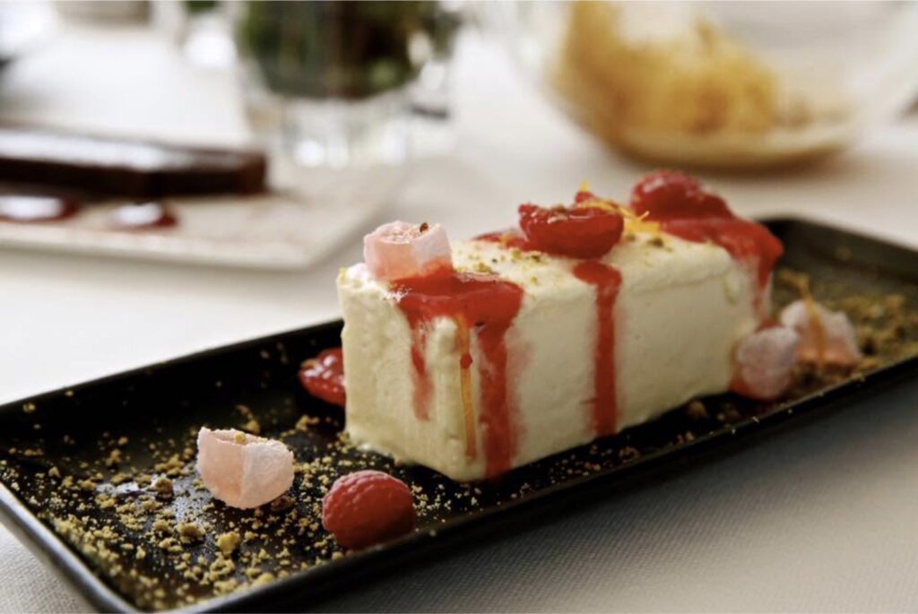 A plated cheesecake with raspberries and rose Turkish delight