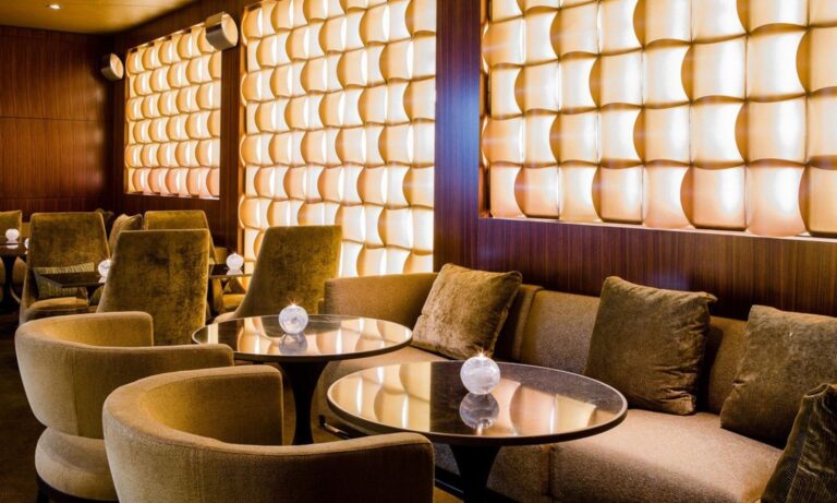 The lounge at ONYX Bar, Park Hyatt Zurich, with backlit onyx wall panels and velvet armchairs