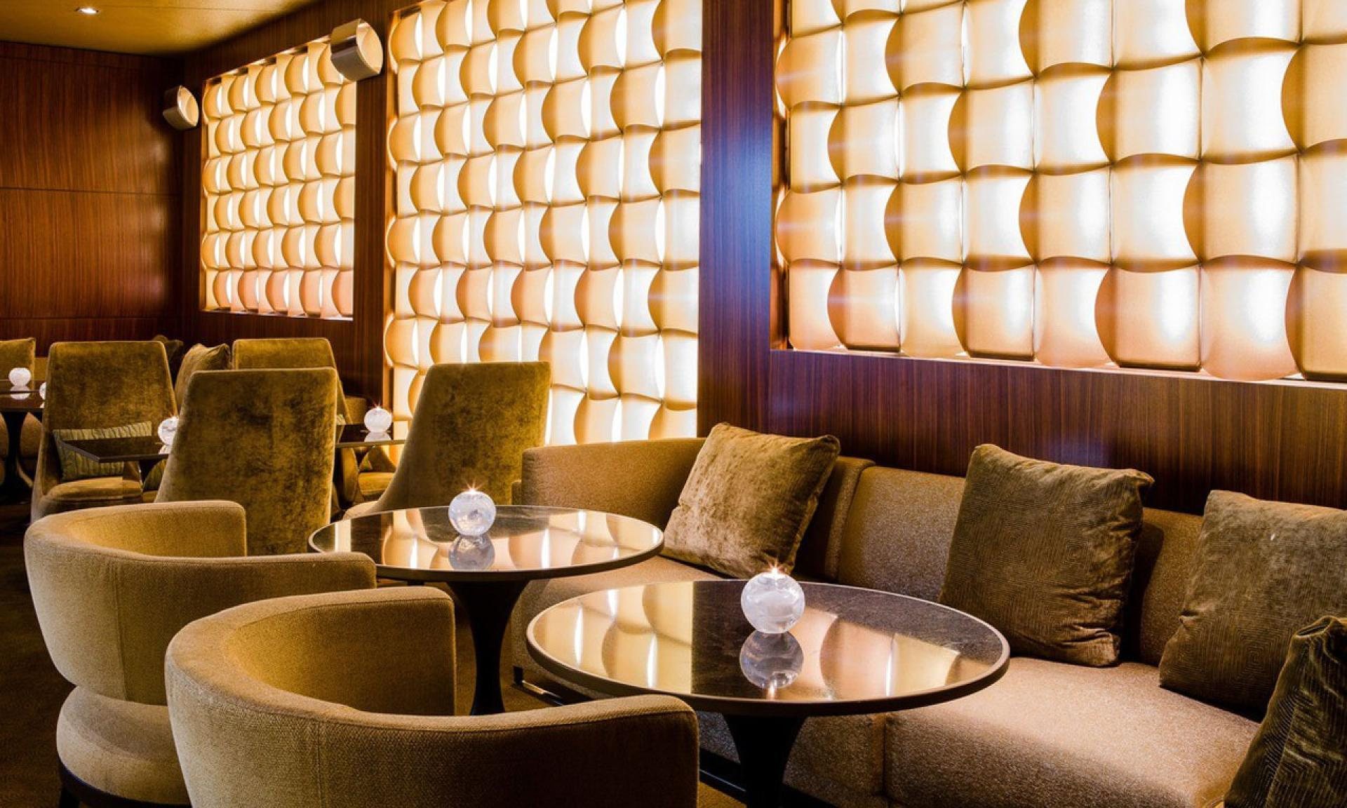 The lounge at ONYX Bar, Park Hyatt Zurich, with backlit onyx wall panels and velvet armchairs
