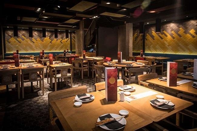 A Ping Pong dining room with timber tables and a gold patterned wall