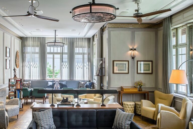 The lounge at The Norman Tel Aviv, with high windows, ceiling fans and deep sofas